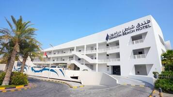 A modern hotel with multiple balconies, a prominent entrance, and a clear sky.