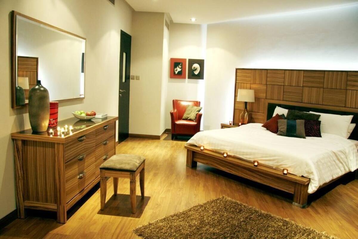 Ein Schlafzimmer mit einem hölzernen Bett, einem Nachttisch, einer Kommode, einem Stuhl und einem Spiegel.