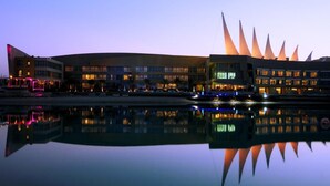 Ein modernes Gebäude mit einem einzigartigen architektonischen Design und einem gro ßen, reflektierenden Wasserspiegel davor.