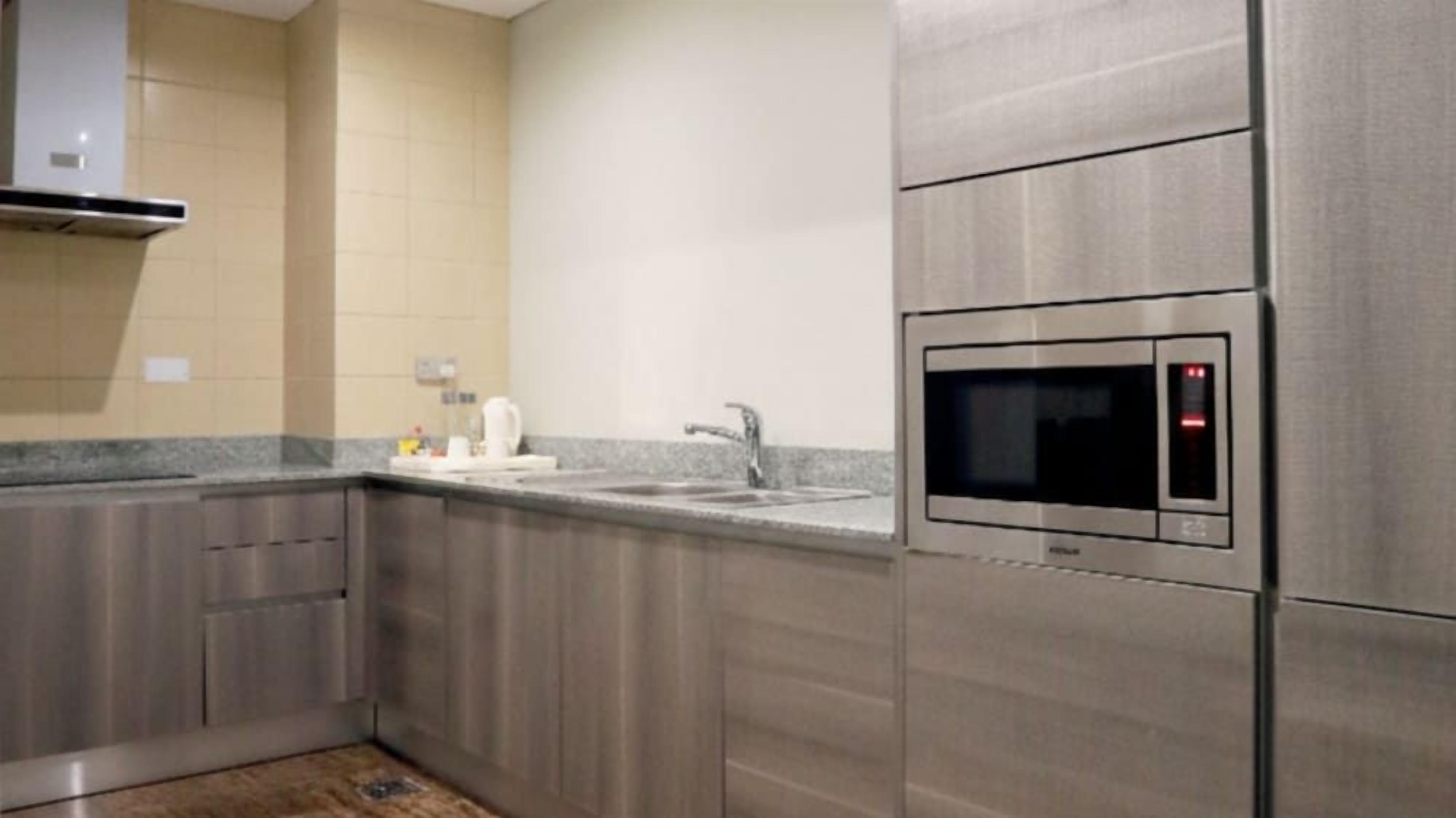 Una cocina moderna con electrodomésticos de acero inoxidable, microondas integrado y encimera de granito.
