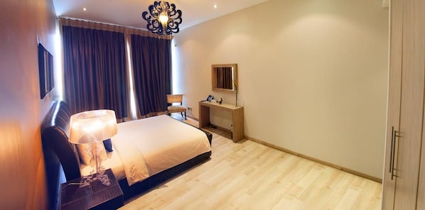 A bedroom with a bed, bedside table, lamp, desk, chair, and wardrobe. - The Dragon Beach Hotel & Resort (Amwaj Islands)