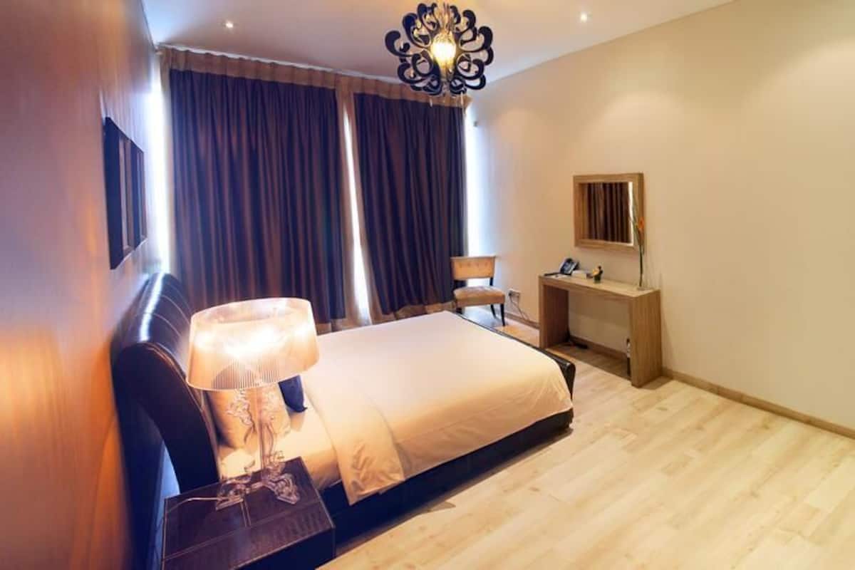 A bedroom with a bed, bedside table, lamp, desk, chair, and wardrobe.