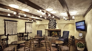 A cozy dining area with wooden tables and chairs, a fireplace, and a television on the wall. - Helendorf River Inn, Suites & Conference Center (Helen)