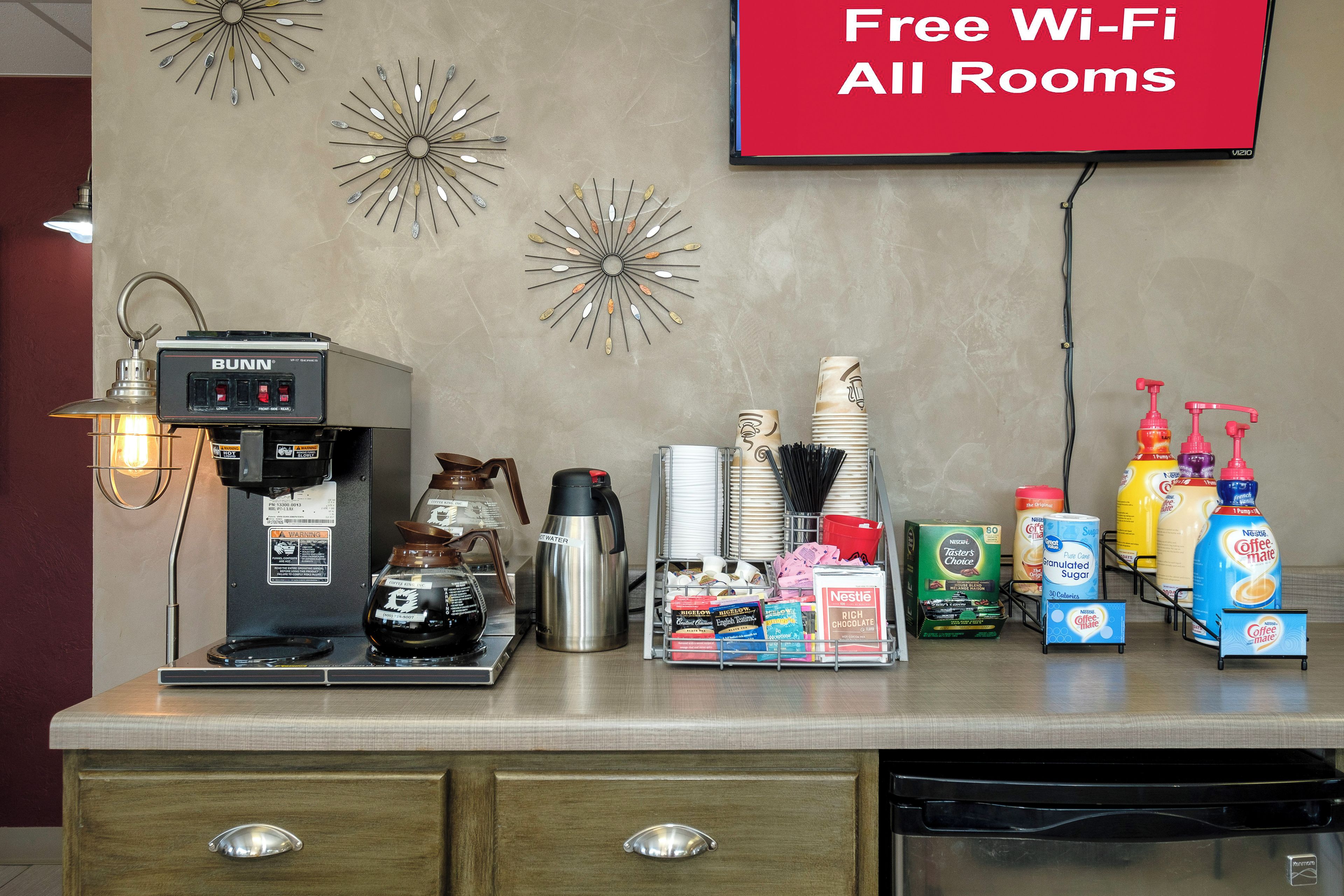 Una estación de café con una máquina de espresso Bunn, un dispensador de agua caliente y diversos productos de café.