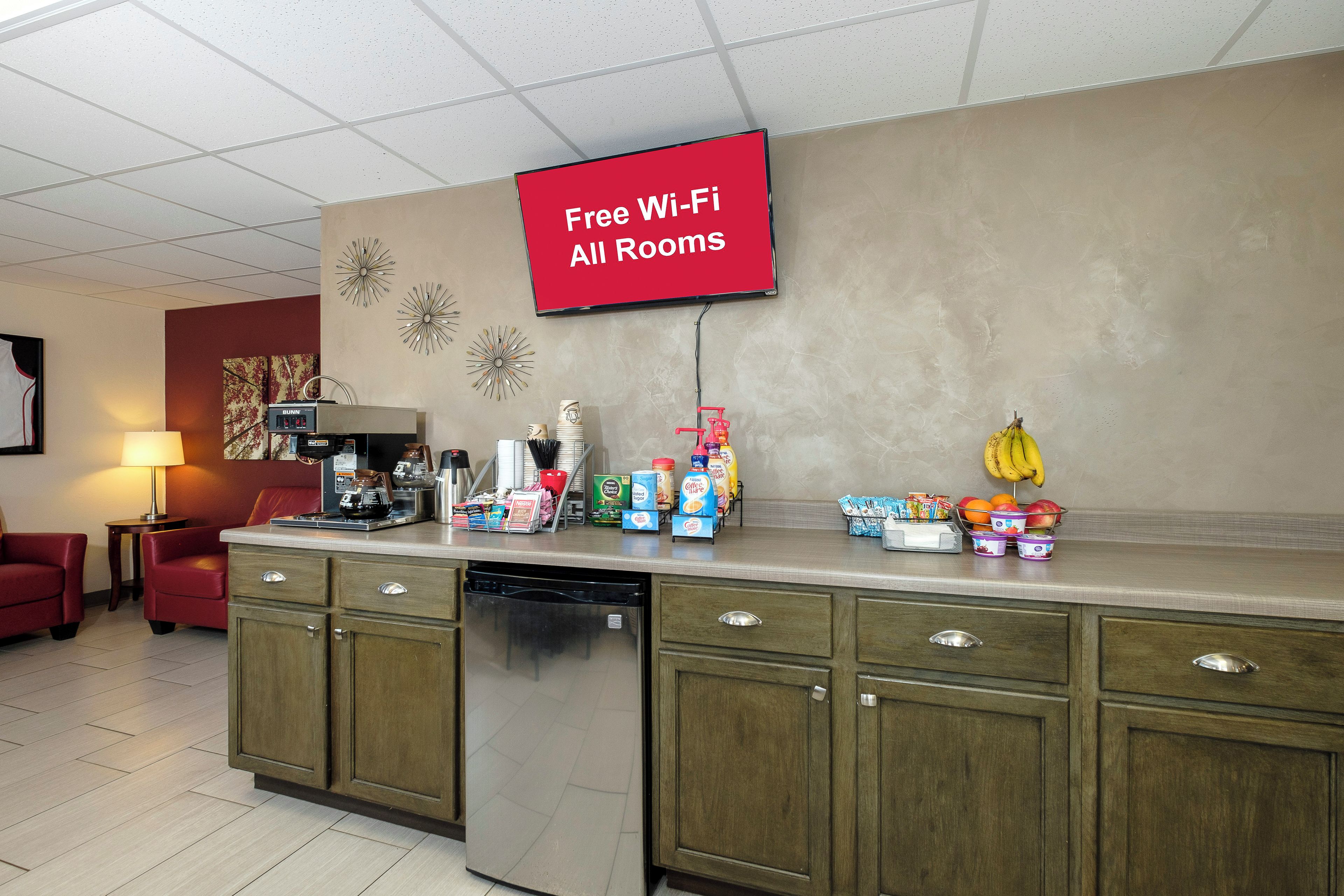 A kitchenette with a coffee machine, a refrigerator, and a sign indicating free Wi-Fi availability.