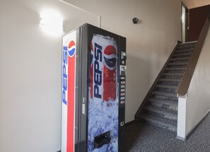 A vending machine with Pepsi branding in a hallway with a staircase. - Red Roof Inn Vermillion - U of South Dakota (Vermillion)