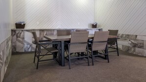 A covered outdoor seating area with a table and chairs, a bench, and a wall with a herringbone pattern. - Red Roof Inn Vermillion - U of South Dakota (Vermillion)