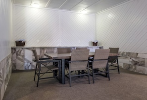 A covered outdoor seating area with a table and chairs, a bench, and a wall with a herringbone pattern. - Red Roof Inn Vermillion - U of South Dakota (Vermillion)