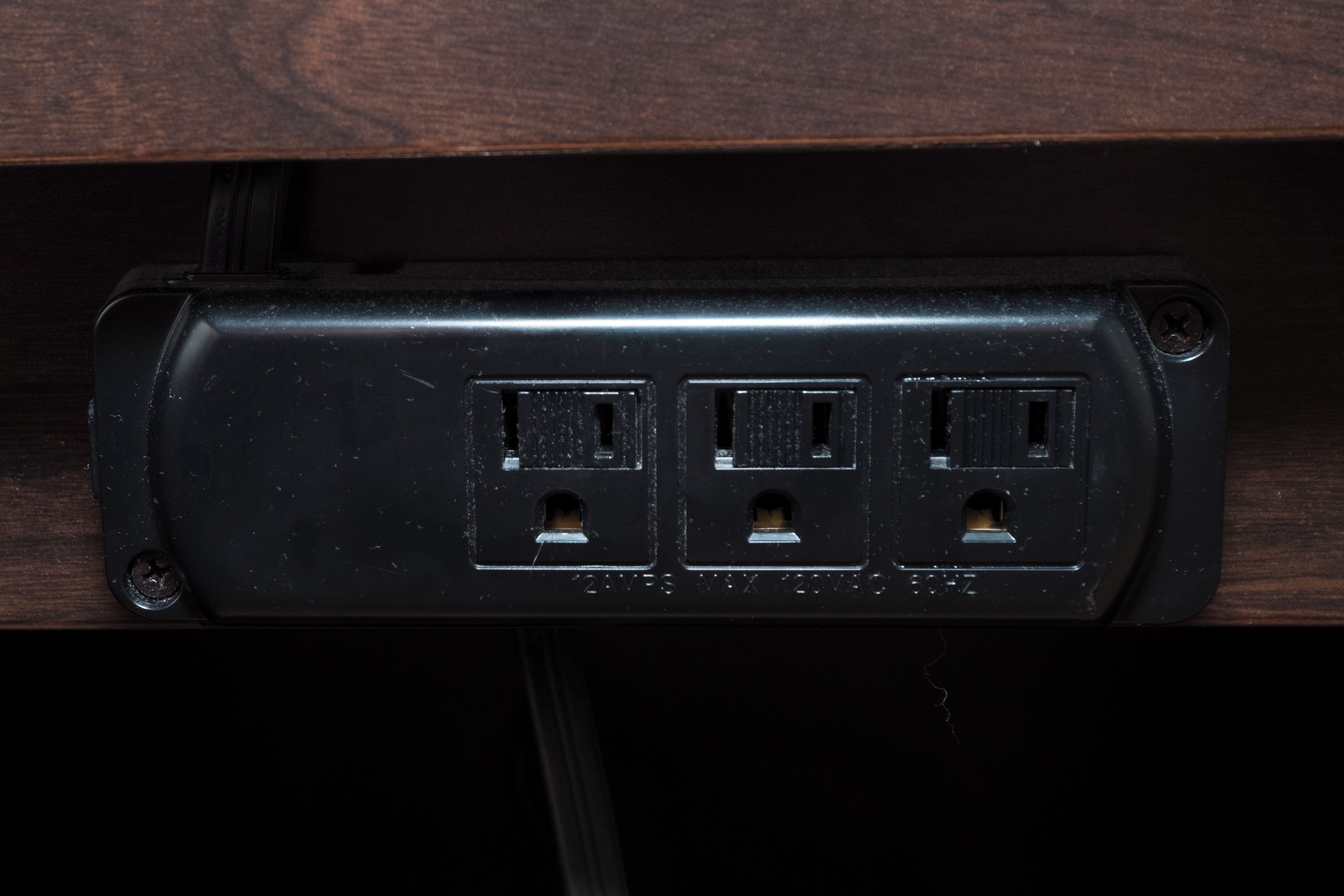 Une prise électrique noire à trois prises, avec une vis sur le côté gauche et un câble qui y est connecté.
