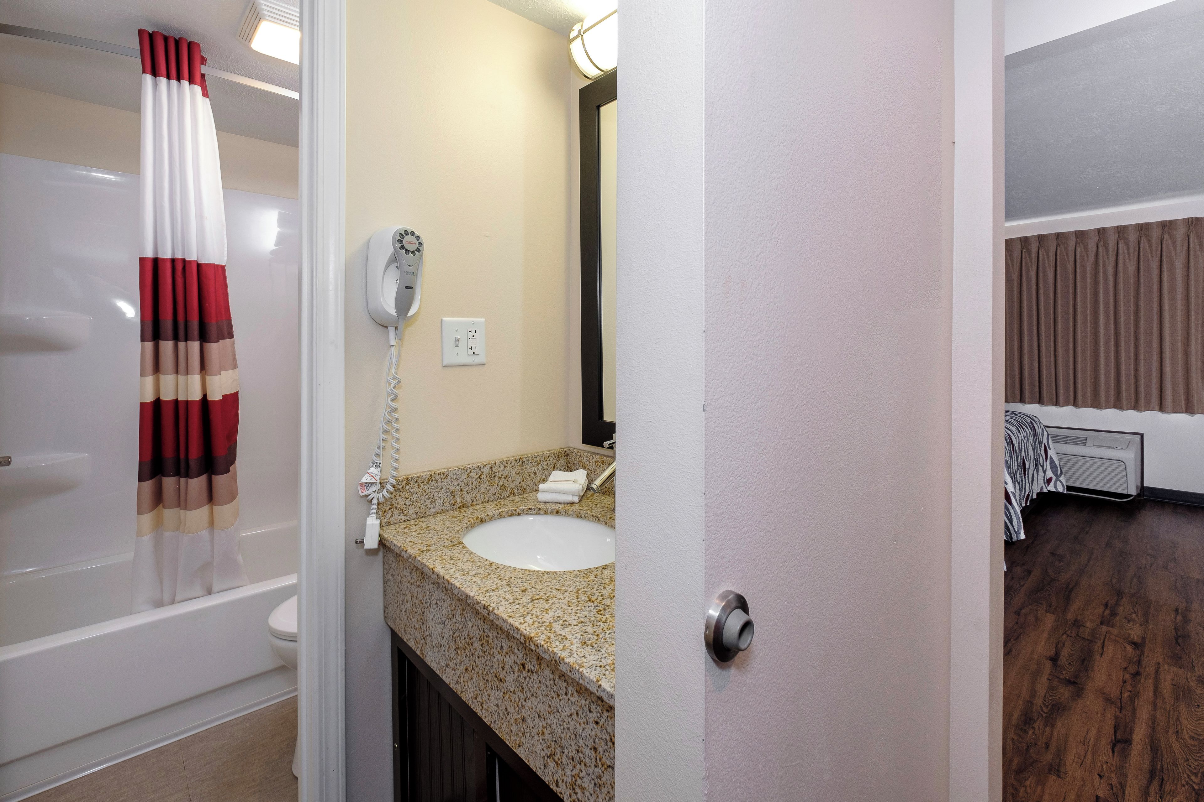 Un baño con lavamanos blanco, secador de pelo y toalla sobre el mostrador.