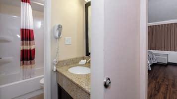 Un baño con lavamanos blanco, secador de pelo y toalla sobre el mostrador.