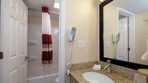 A bathroom with a shower curtain, a hairdryer, a sink, and a mirror. - Red Roof Inn Vermillion - U of South Dakota (Vermillion)