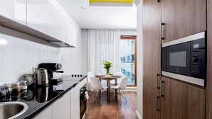 Une cuisine moderne avec des armoires blanches, un comptoir noir, un four à micro-ondes encastré et un coin repas comprenant une table et des chaises.