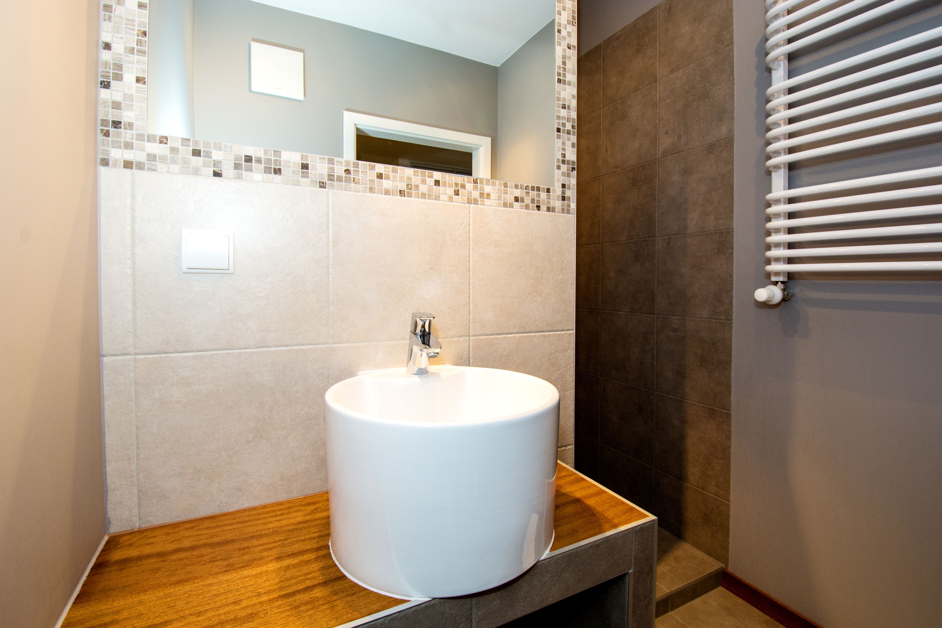 A bathroom with a white sink, a wooden countertop, a tiled backsplash, and a towel rack.