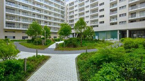 Un immeuble d’appartements moderne, doté de plusieurs étages, d’une cour aménagée et d’un chemin piétonnier pavé.