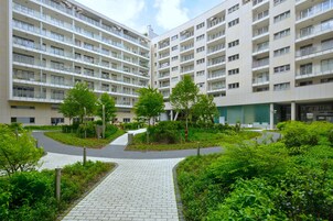 Moderni kerrostalo, jossa on useita kerroksia, maisemoitu sisäpiha ja päällystetty kävelyreitti.