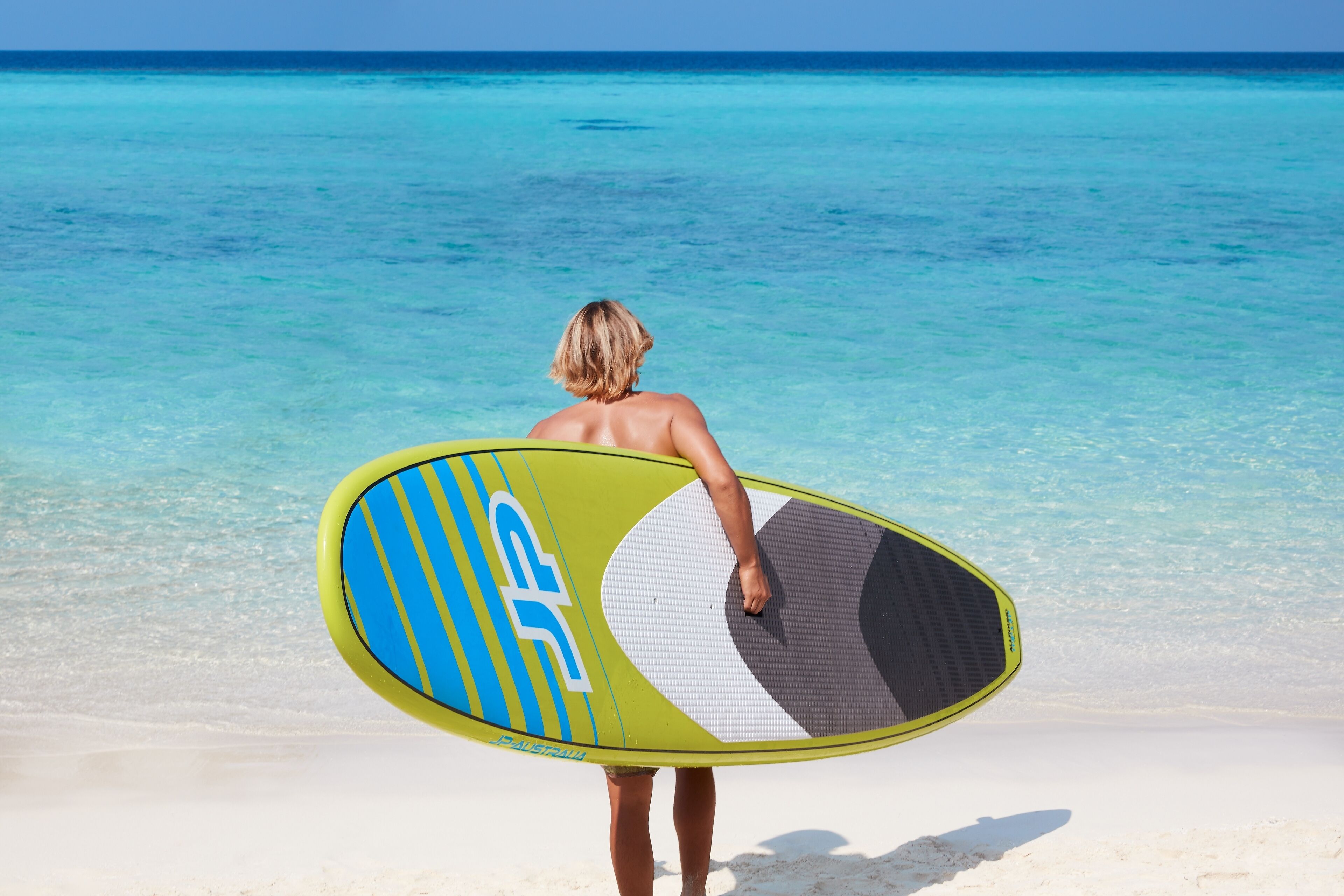 A person holding a surfboard on a beach.