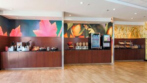 Een receptie met een houten balie, een digitale kiosk en een presentatie van fruit.
