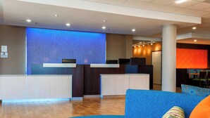 Een moderne receptie met een blauwe wand met structuur, een receptiebalie en een blauwe bank met opvallende kussens.