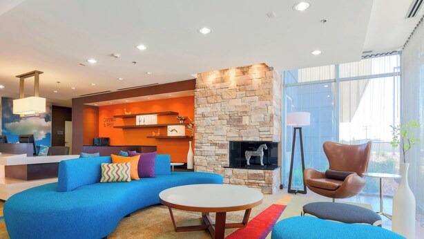Een moderne woonkamer met een blauwe bank, een ronde salontafel en een stenen open haard.