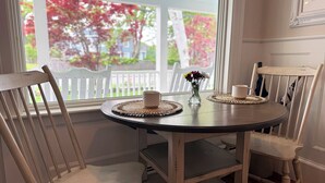 A dining table with a vase of flowers, a mug, and a woven placemat.