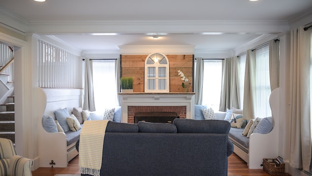 A living room with a fireplace, a sofa, and a staircase.