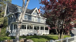 A two-story house with a porch, a flag, and a sign indicating no vacancies.