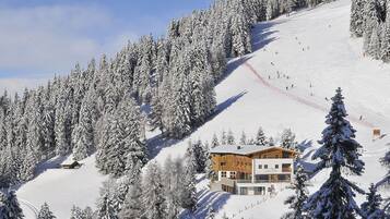 Montanha coberta de neve com uma hospedaria e pistas de esqui.
