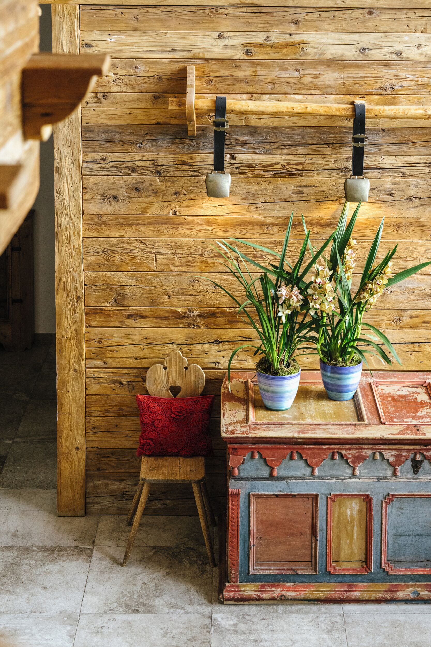 Een rustieke houten wand met twee potplanten en een klein houten krukje.