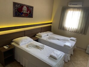 A hotel room with two beds, a nightstand, a wall-mounted air conditioner, and a window with curtains. - Pousada Jovimar (Aparecida)