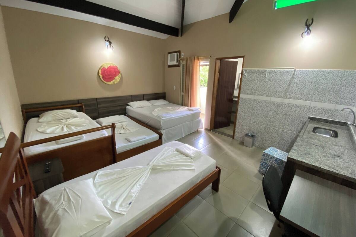 A hotel room with four beds, a bathroom with a sink and mirror, and a door leading outside.