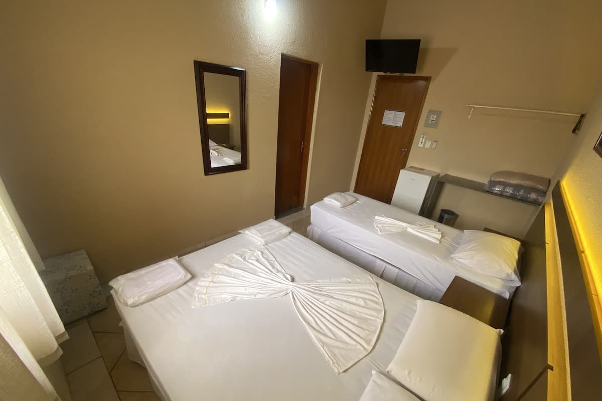 Ett hotellrum med två sängar, en spegel, en tv och ett litet kylskåp.