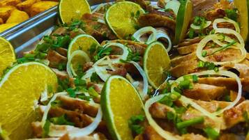 A tray of food with sliced meat, lime, and chopped green onions.