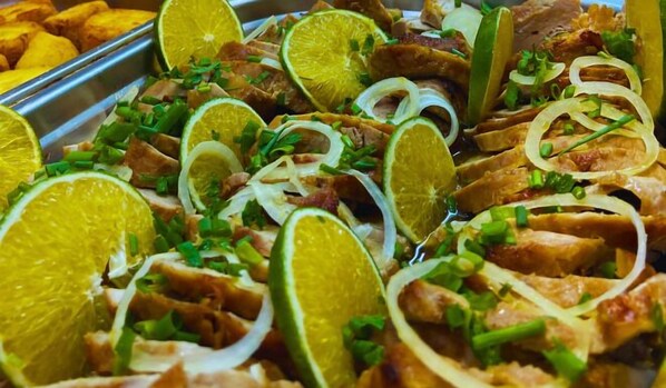 A tray of food with sliced meat, lime, and chopped green onions. - Pousada Jovimar (Aparecida)