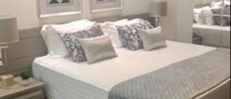 A modern bedroom with a large bed, two bedside tables, and a mirror.