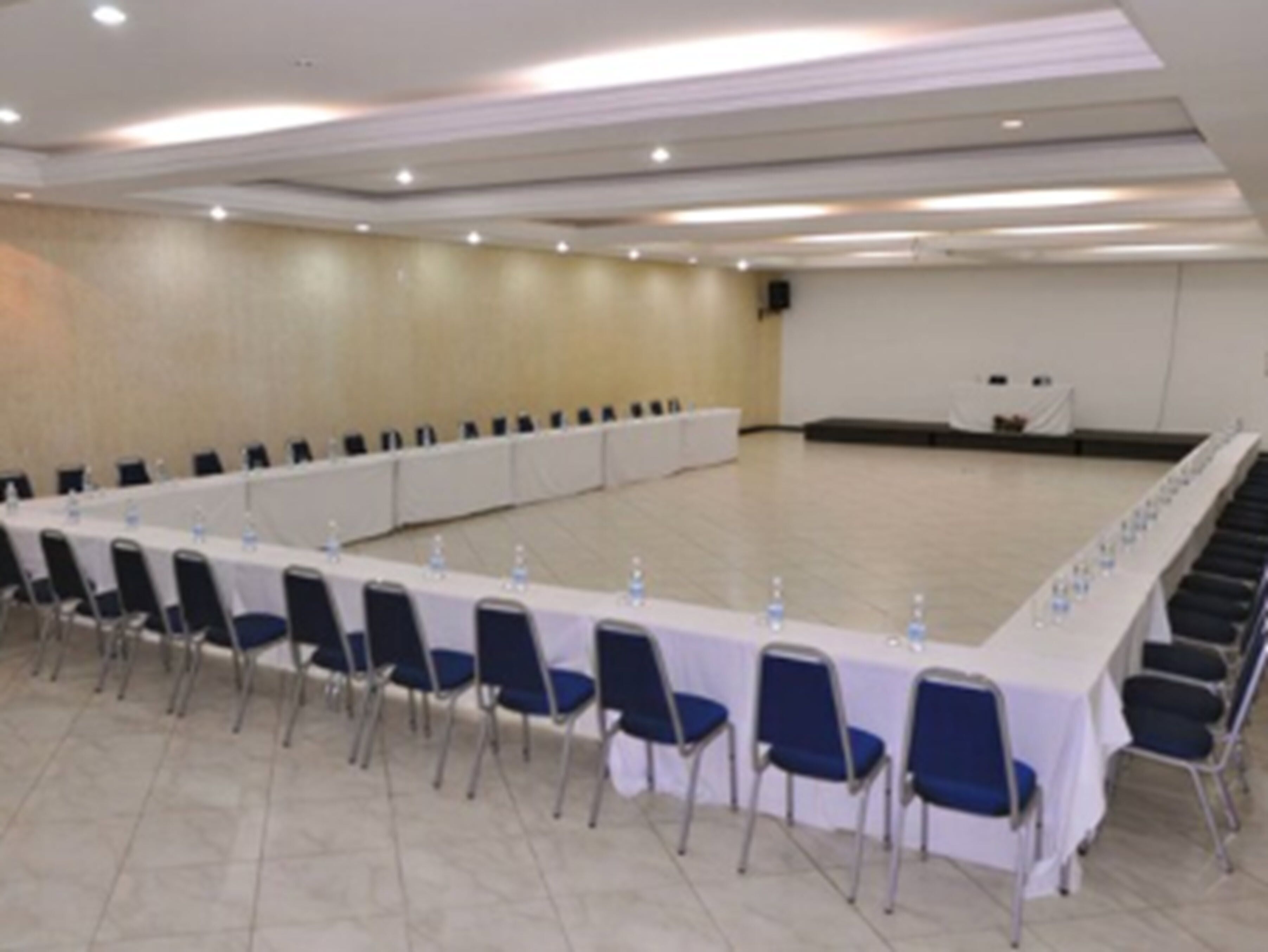 A conference room with a long table, chairs, and a stage area.