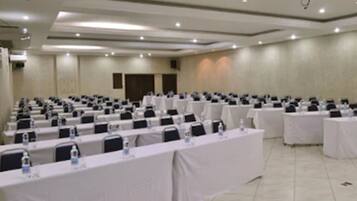 Un salón de conferencias con filas de mesas, cada una con tarjetas de identificación y botellas de agua.