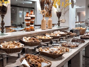 A buffet with various breads and pastries displayed in baskets and on trays. - Hotel Guarany (Águas de Lindóia)