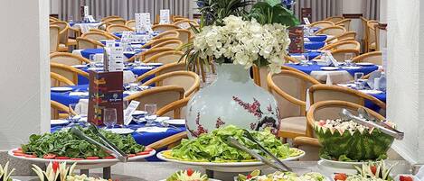 A buffet setup with various food items and a decorative vase.