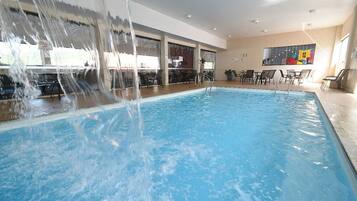 Alberca techada, alberca al aire libre y sombrillas en la alberca