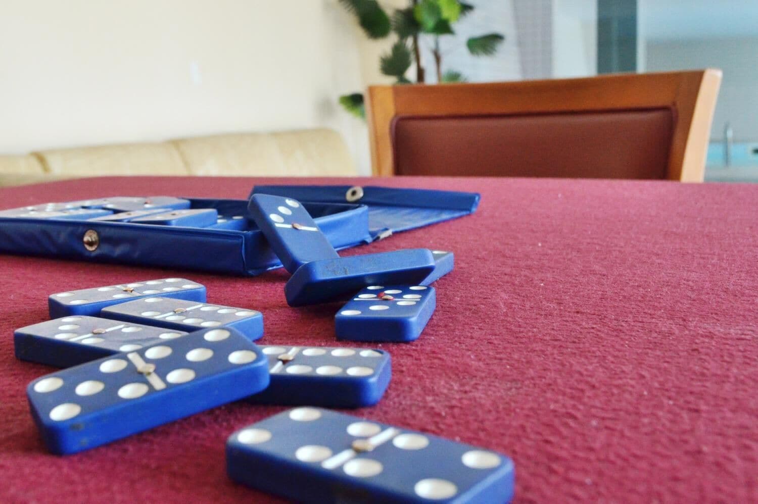 Una mesa con fichas de dominó azules esparcidas sobre un mantel rojo.