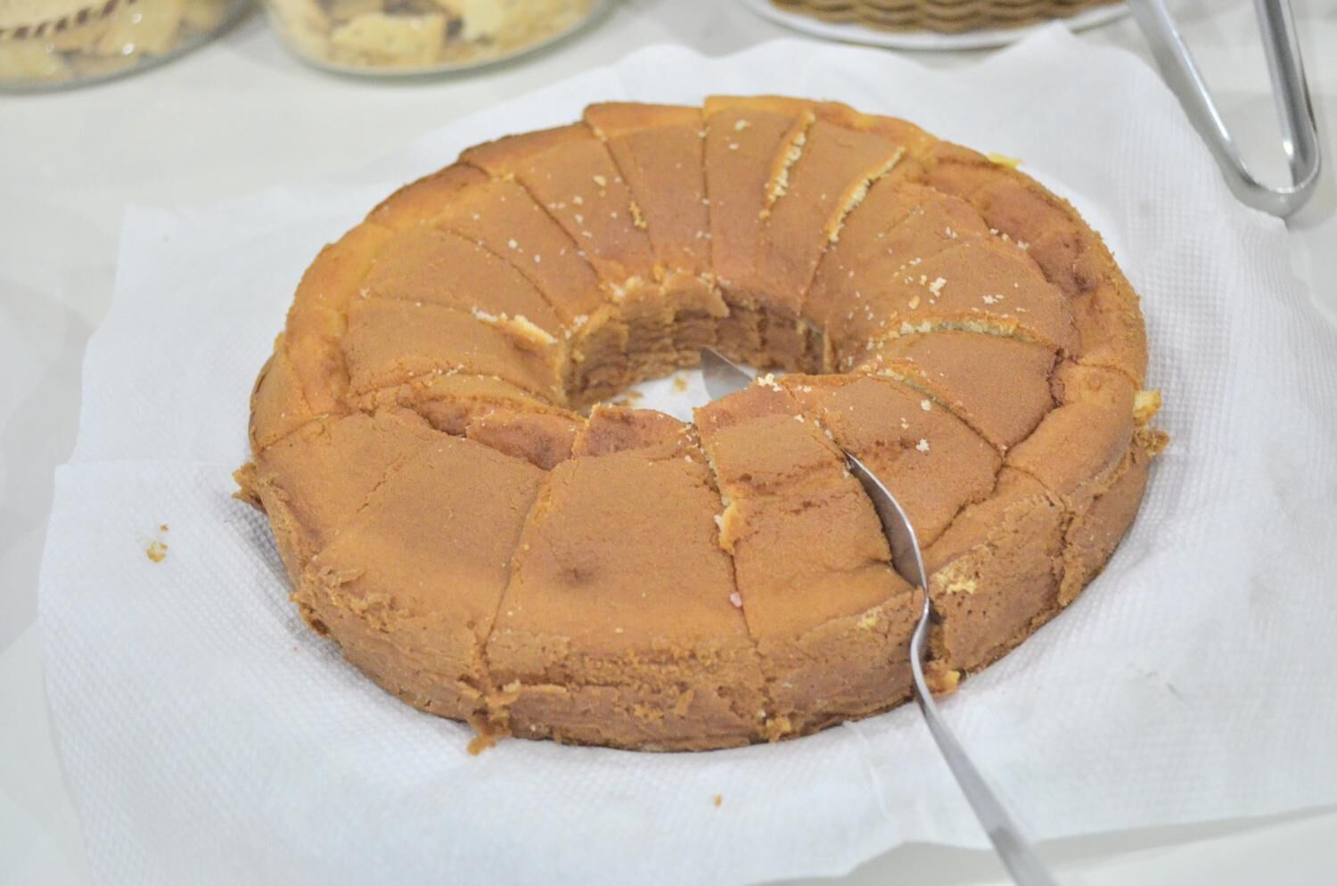 A round cake with a knife in it, placed on a white paper.