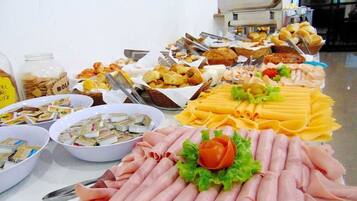 Un bufé con diversos alimentos, incluyendo carnes, quesos y pasteles.