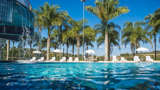 Una piscina amb aigua turquesa, envoltada de gandules blanques i palmeres.