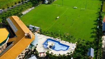 Vue aérienne d’un hôtel doté d’une piscine, d’un terrain de football et d’un parking.