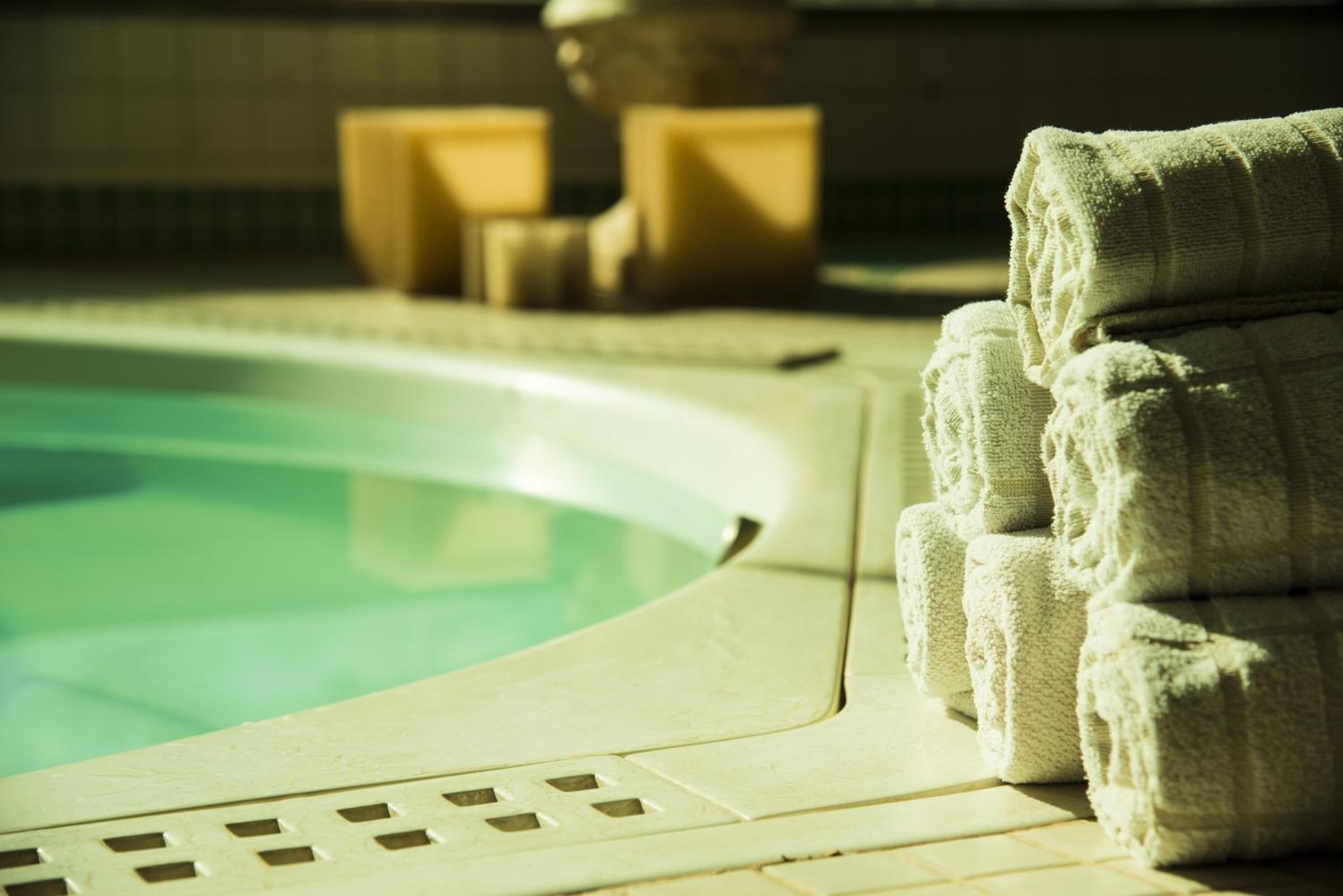 A pool area with a tiled edge and a stack of towels.
