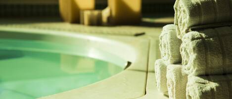 A pool area with a tiled edge and a stack of towels.