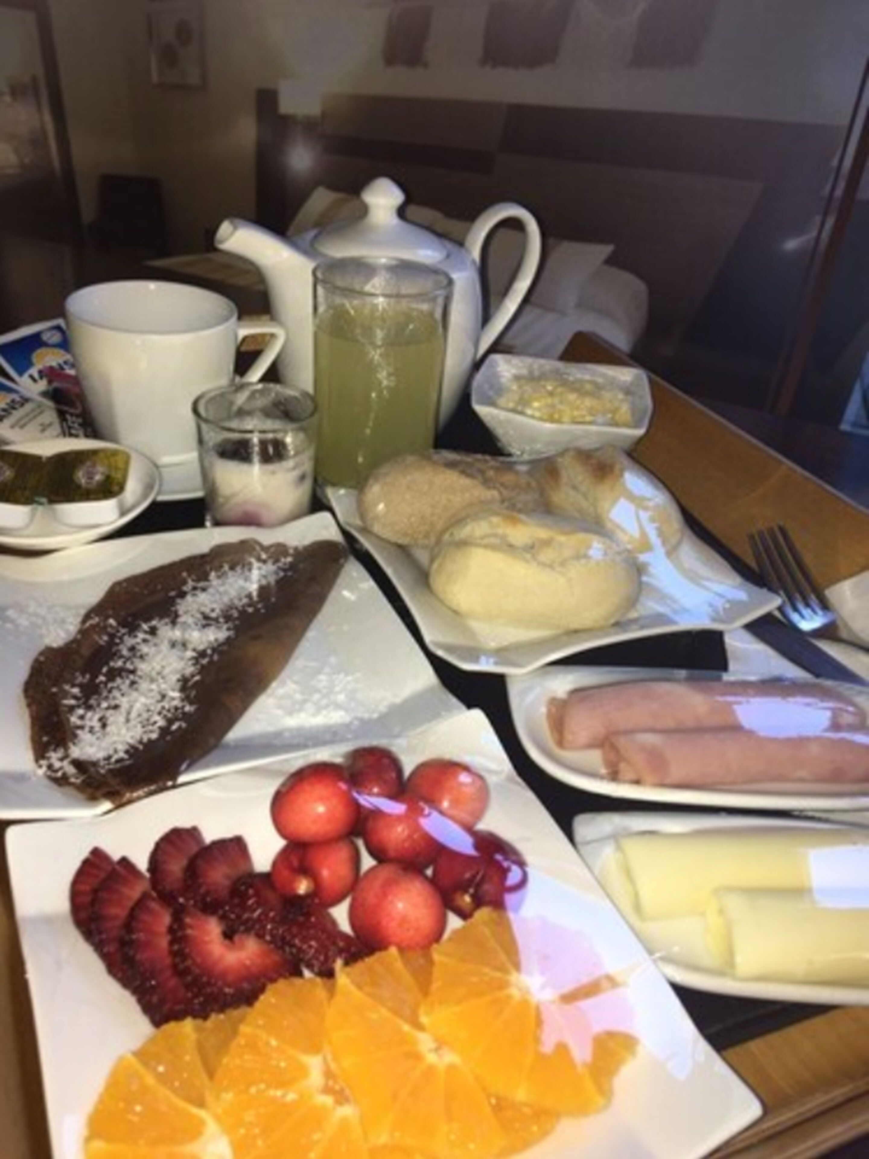 A breakfast table with various food items including toast, fruit, and a beverage.