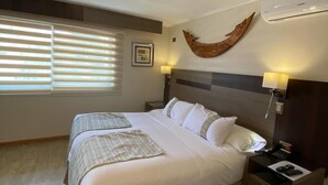 A hotel room with a large bed, bedside tables, a wall-mounted air conditioner, and a window with blinds. - Hotel Boutique Reyall (Santiago)