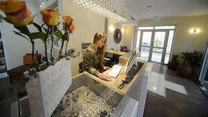 A reception desk with a woman working, surrounded by decorative glassware and vases. - Hotel Boutique Reyall (Santiago)